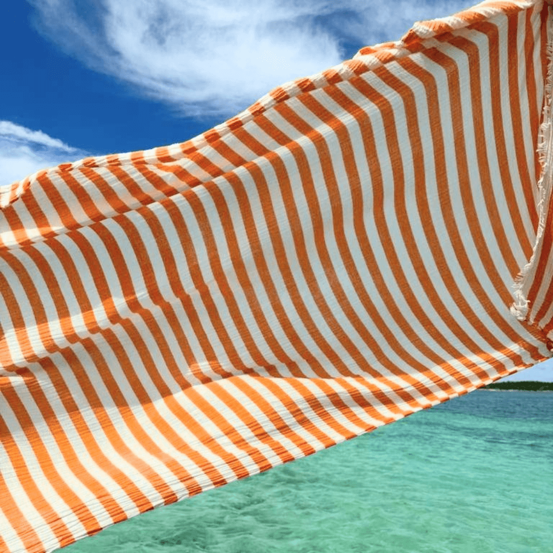extra large oversized muslin turkish beach towel, flat woven peshtemal, waving with wind on a boat orange stripes