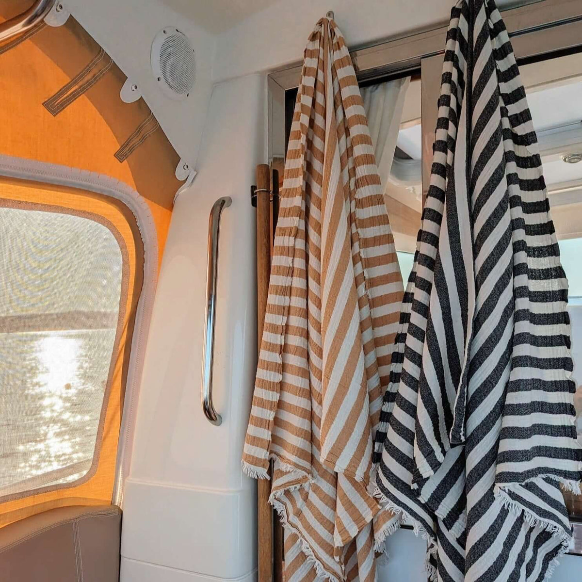 brown and black stripes on white Turkish towels are hanging dry on the boat 