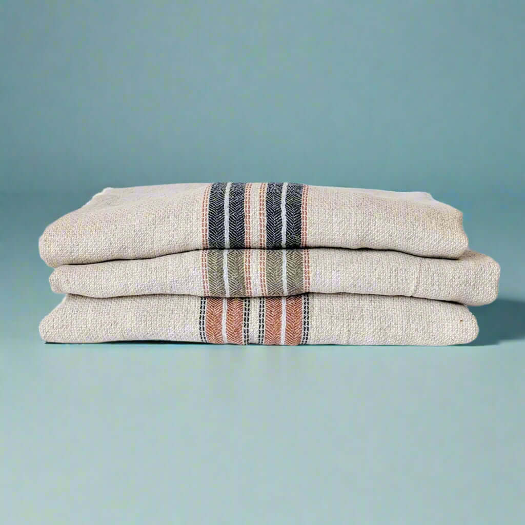 Terra red, navy blue and green hestia turkish towels folded and stacked on top of each other 