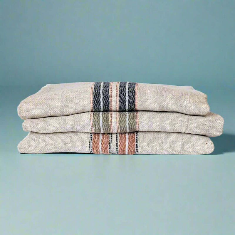 Terra red, navy blue and green hestia turkish towels folded and stacked on top of each other 
