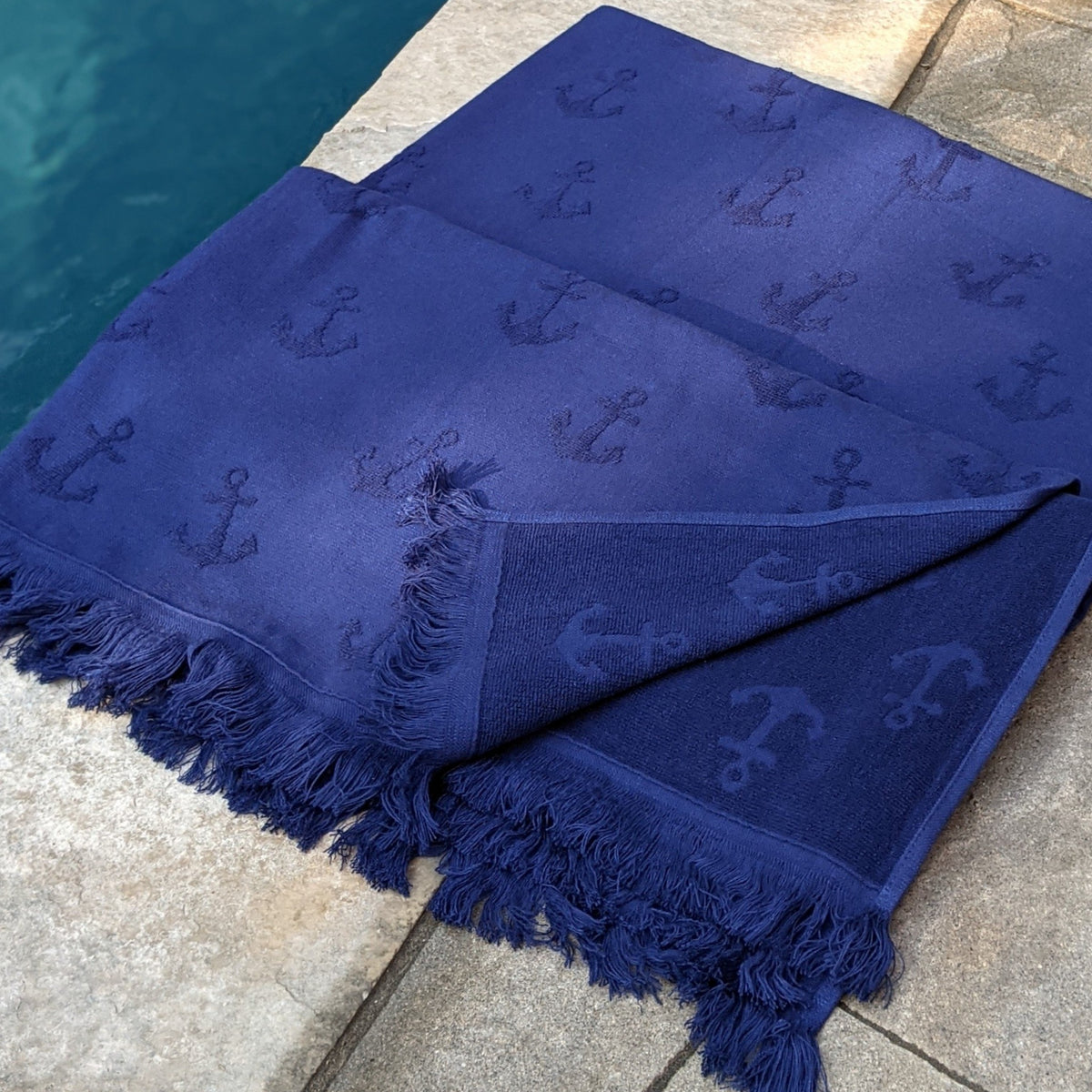 navy Turkish Towel with anchor design one side terry with fringes near pool