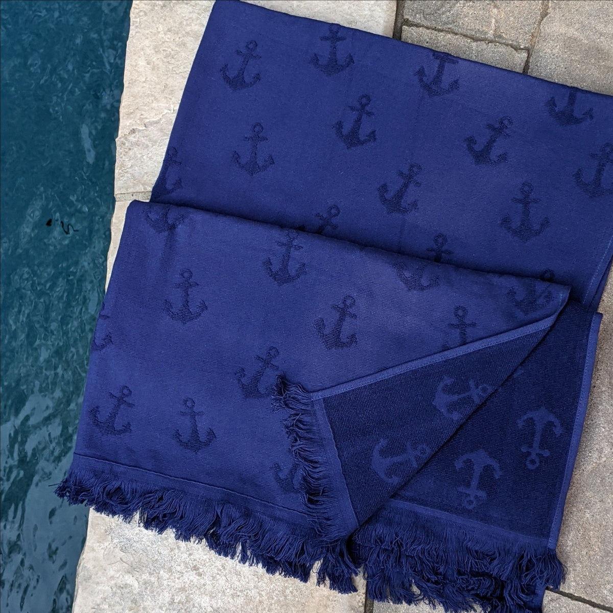 navy Turkish Towel with anchor design one side terry with fringes near pool